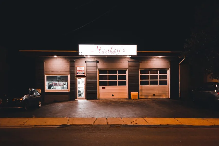 The front of the shop at dusk with the bay doors lit