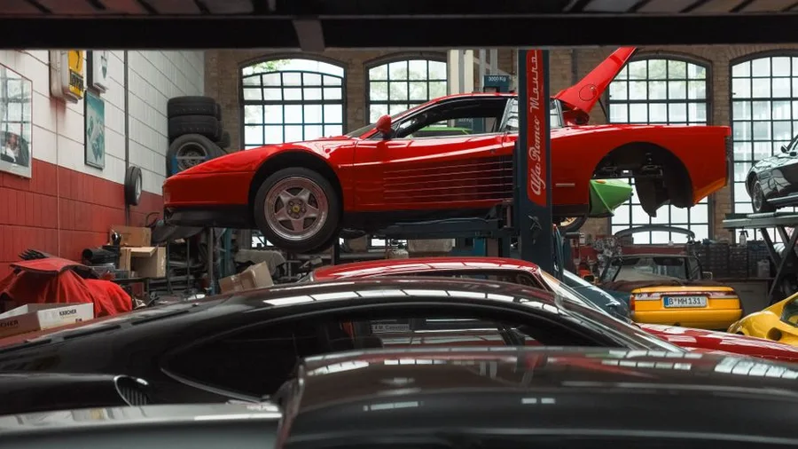 A sports car raised on a two-post lift in the bay