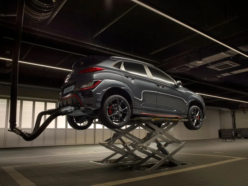 A car raised on a scissor lift in a dark, clean service bay