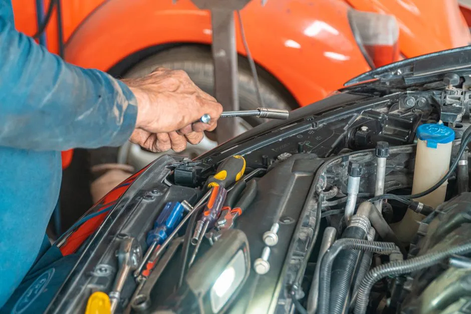Hands working on an engine with the wheel off and the car on a lift