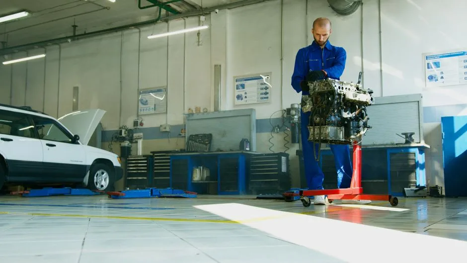 A technician performing an oil service on a car raised on the shop lift