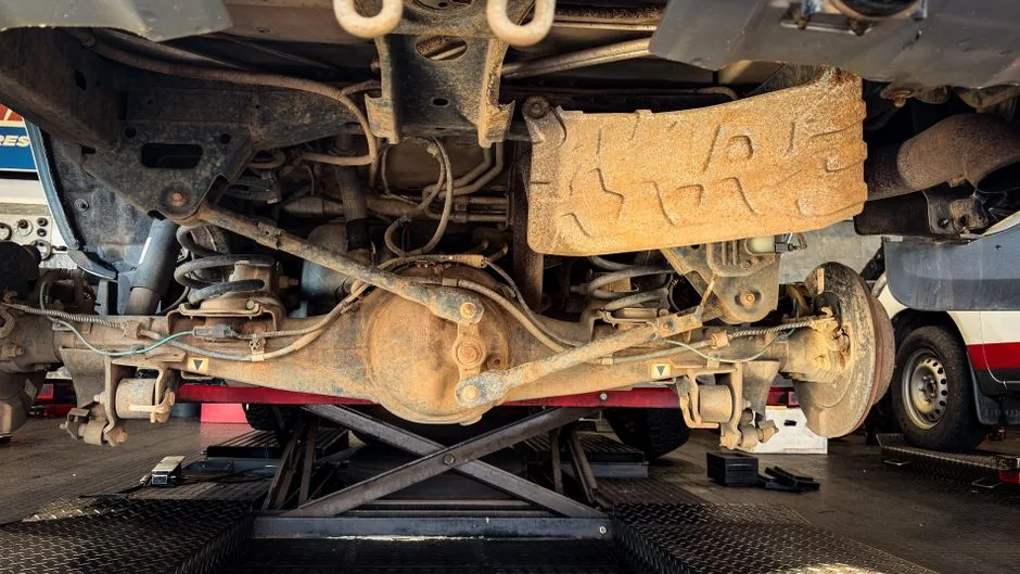 The underside of a car on a lift during a pre-purchase inspection